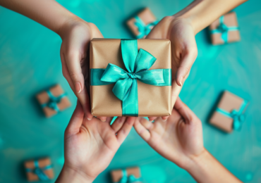 four hands holding a gift box with a teal bow