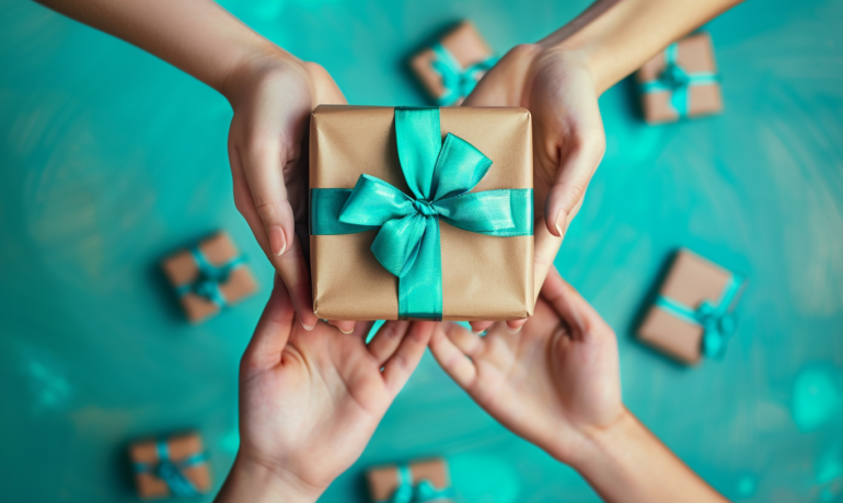 four hands holding a gift box with a teal bow