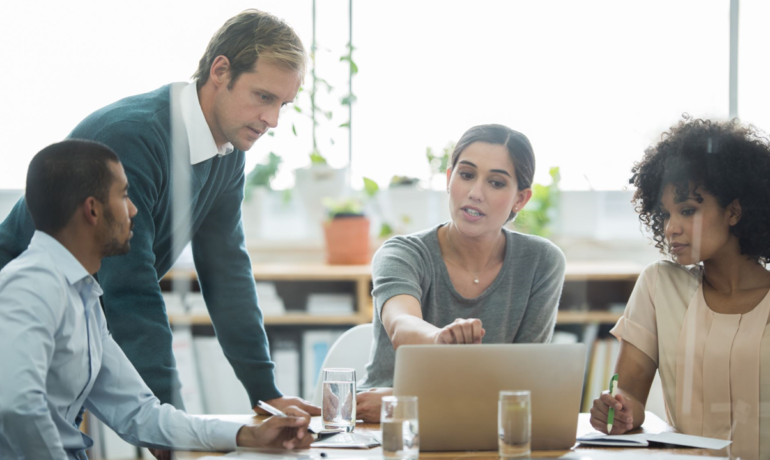 Stock photo of four diverse people sitting and standing around a computer screen